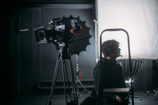 The director of photography holds a camera in his hands on the set in the pavilion. A professional videographer films a movie, commercial or TV series in a studio.