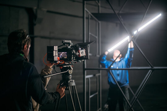 The director of photography holds a camera in his hands on the set in the pavilion. A professional videographer films a movie, commercial or TV series in a studio.