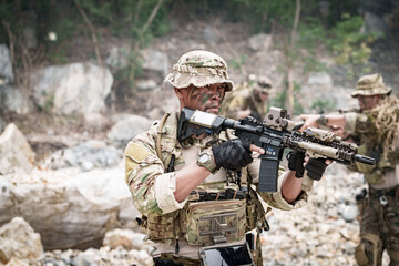 Fototapeta premium Special forces soldier in camouflage gear aiming a rifle during a tactical operation