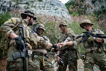 Fototapeta premium Special forces soldiers in camouflage gear huddle together in a rocky, wooded area