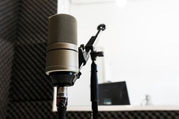 Close-up of a professional studio microphone on a boom arm with a bright, blurred control room background. © MatiasLeonel