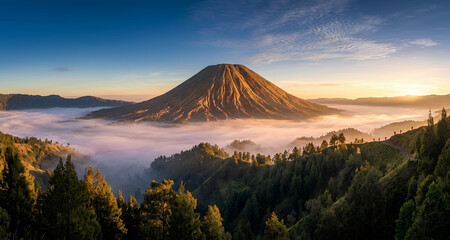 Fototapeta premium A breathtaking panoramic landscape of a majestic, deeply ridged volcanic cone rising above a thick, rolling sea of morning mist. Warm golden sunrise light bathes the right side of the mountain and the