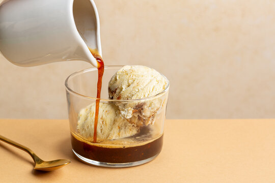 Making Affogato, or affogato al caff&egrave;, is an Italian ice cream dessert comprising a scoop of gelato, topped with espresso.  Horizontal image, beige background, copy space.