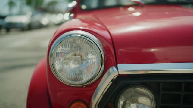 Detailed cinematic footage of classic red vintage automobile exterior with soft focus background and polished retro design elements in sunny outdoor setting
