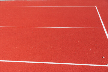 Fototapeta premium Bright Red Tennis Court Surface Inviting Players for a Lively Match Under the Clear Blue Sky in the Afternoon Sun