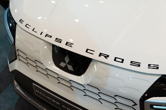 LISBON, PORTUGAL - MAY 16, 2026: Angle close-up view of the black Eclipse Cross bonnet lettering, Mitsubishi three-diamond logo, and front grille on a white vehicle at the ECAR Show exhibition