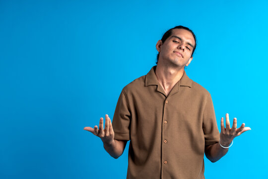 Young man shrugging shoulders expressing indifference or uncertainty