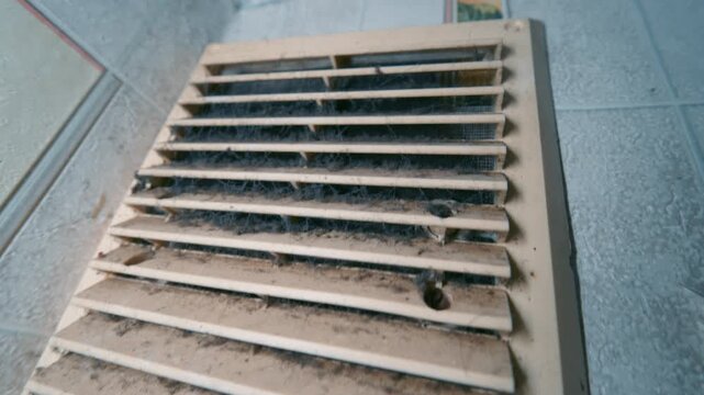 Dirty Dusty Air Vent Grille on Tile Wall Covered with Dust and Cobwebs | Slow Tilt Up Close-Up Shot | HVAC Maintenance and Air Quality Concept