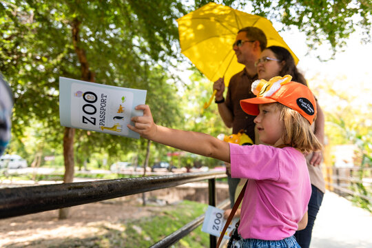 Child with a zoo passport and family on a sunny day at the zoo.