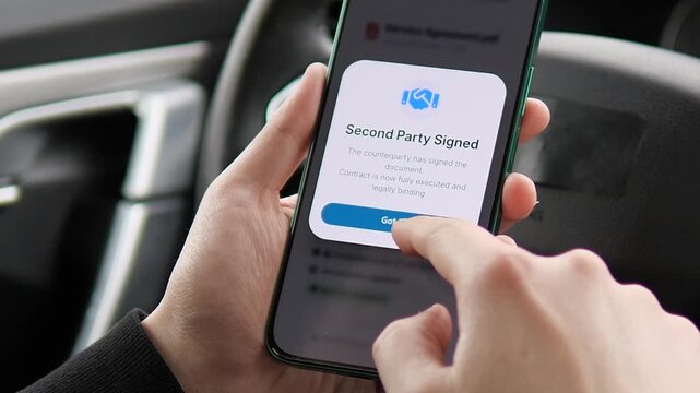 Hands in a car finalizing business deals. Smartphone screen shows Second Party Signed contract confirmation. Perfect for digital signature apps, legal tech, and corporate workflow visualization.