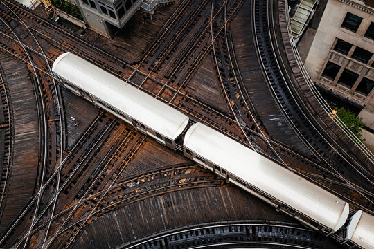 High angle view of commuter train passing elevated railway track junction in downtown Chicago city center. Urban transport, transit infrastructure and public transportation concept.