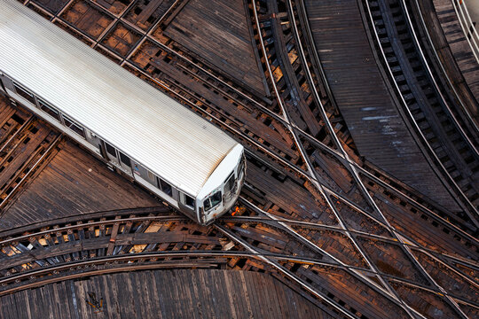 High angle view of commuter train passing elevated railway track junction in downtown Chicago city center. Urban transport, transit infrastructure and public transportation concept.