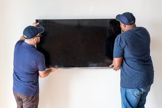 Men installing flat-screen television photo