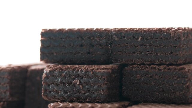 Hand stacking crispy wafers with chocolate filling on a white background, sweet confectionery.
