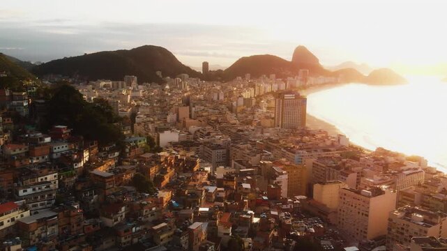 Drone pulls back over Rio favela revealing Copacabana Beach at golden sunset