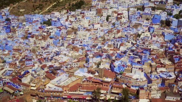 Drone top-down tilts to reveal Chefchaouen's iconic blue medina and dry Rif hills.