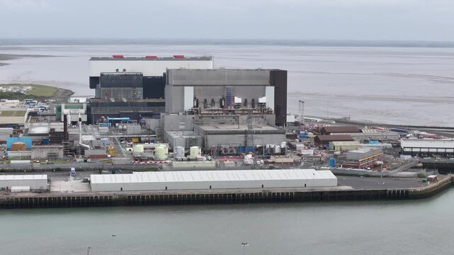 Heysham nuclear power stations UK aerial pan to wind turbine coming into shot