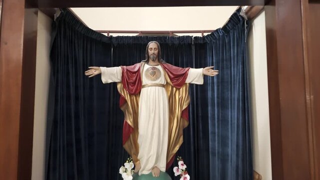 Dolly back reveal of Sacred Heart statue inside Catholic church interior