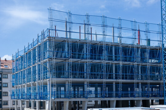 Building construction site with blue safety netting and scaffolding