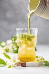 Fototapeta premium Green jasmine tea with macha latte in glass with jasmine flowers. Trendy drink