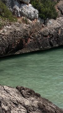 Rocky shoreline and calm turquoise water at Cala Ferrera, Mallorca, showcasing the natural beauty of a Mediterranean cove on a sunny summer afternoon.