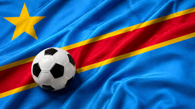A classic black and white soccer ball placed on top of the rippled, textured flag of the Democratic Republic of the Congo, representing sports and national pride.