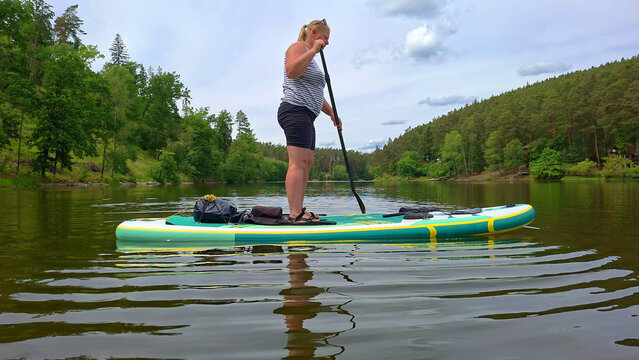 Woman on a paddleboard enjoying summer vacation on a mountain lake.