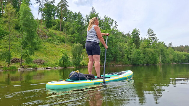 Woman on a paddleboard enjoying summer vacation on a mountain lake.