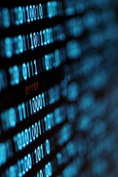 Binary code with small red error on blurred computer screen
