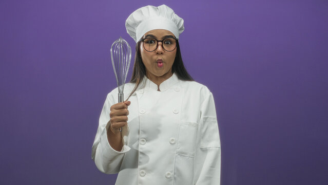 Young woman chef in white coat and hat holds whisk up and smiles toward camera in studio with purple backdrop, wearing glasses and showing varied playful expressions across frames; playful joy.