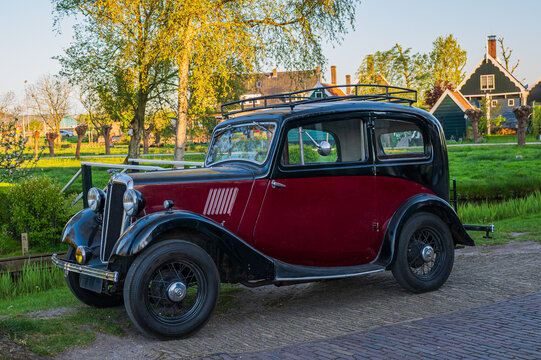 Amsterdam, Netherlands, 22.04.2026 - Vintage oldtimer car parked in front of traditional green Dutch house during golden hour
