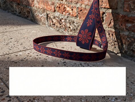 Decorative fabric strap coiled on pavement near brick wall
