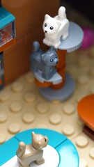 Obraz premium Tambov, Russian Federation - July 05, 2025 Three Lego cats in white, gray and tan colors play on a built scratching post and a colorful floor mat indoors.