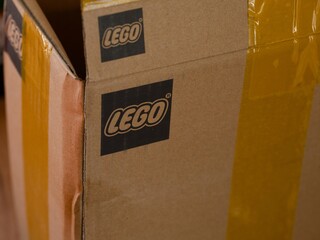 Obraz premium Tambov, Russian Federation - June 03, 2026 A close-up shot of a cardboard box featuring the printed black Lego logo and sealed with yellow adhesive tape.
