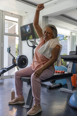 Naklejka premium Flat weight bench is holding towel and orange dumbbells in home gym near windows