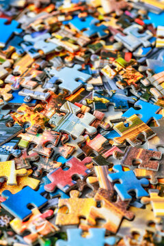 Jigsaw puzzle pieces.Colorful background with small puzzle pieces, messy.Some colored pieces of puzzle as background.Challenge and solution concept. Hobbies and leisure activities