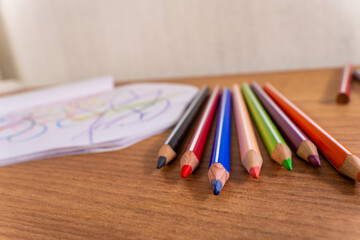 Obraz premium Colorful Pencils Beside Child Drawing Sketchbook
