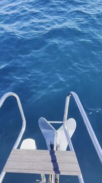 Yacht stern ladder above deep blue ocean water.