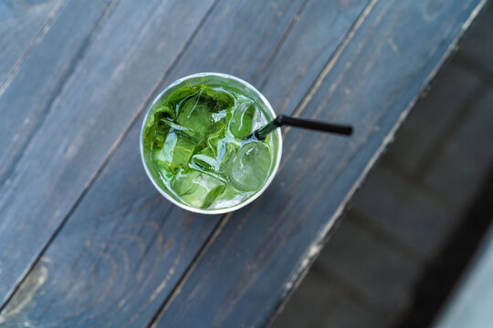 Overhead view of a refreshing iced matcha green tea or mojito on a dark wooden table