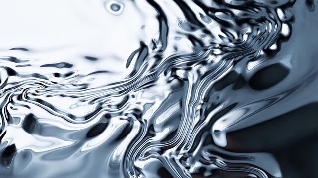 Tracking shot of metallic liquid rippling and flowing across reflective surface on tabletop in studio close up with slow motion pan