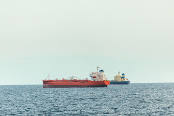 Fototapeta premium Oil tanker and cargo vessel anchored in open sea under calm weather conditions, maritime transportation and global shipping industry