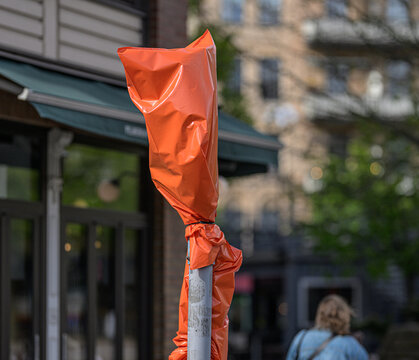 Orange covered traffic sign on city street during roadworks.