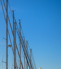 Obraz premium Tall sailboat masts rising against clear blue sky.