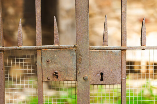 Rusty wrought iron gate with antique lock detail in historic stone village, weathered metal craftsmanship and traditional architecture background