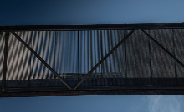 Modern pedestrian bridge silhouette against blue sky.