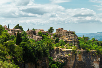 Fototapeta premium Stone village of Siurana perched on dramatic sandstone cliffs in Catalonia Spain overlooking rugged mountain landscape under summer clouds