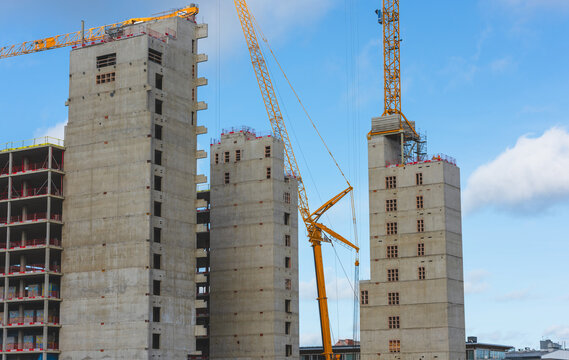 Urban high rise construction project with cranes and concrete towers.