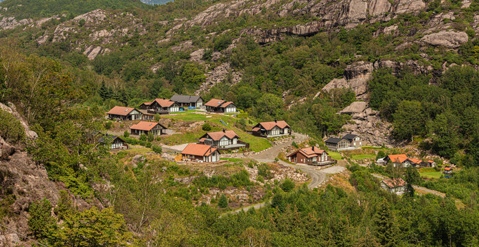 Scenic mountain village with cabins in rocky green landscape.