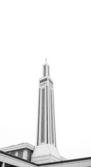 Obraz premium A tall, slender minaret of a mosque rendered in stark black and white, featuring a square base, multiple levels with decorative geometric latticework, and a pointed spire, set against a