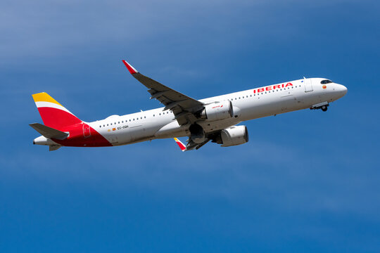Iberia Airbus commercial airplane taking off and climbing under a bright blue sky